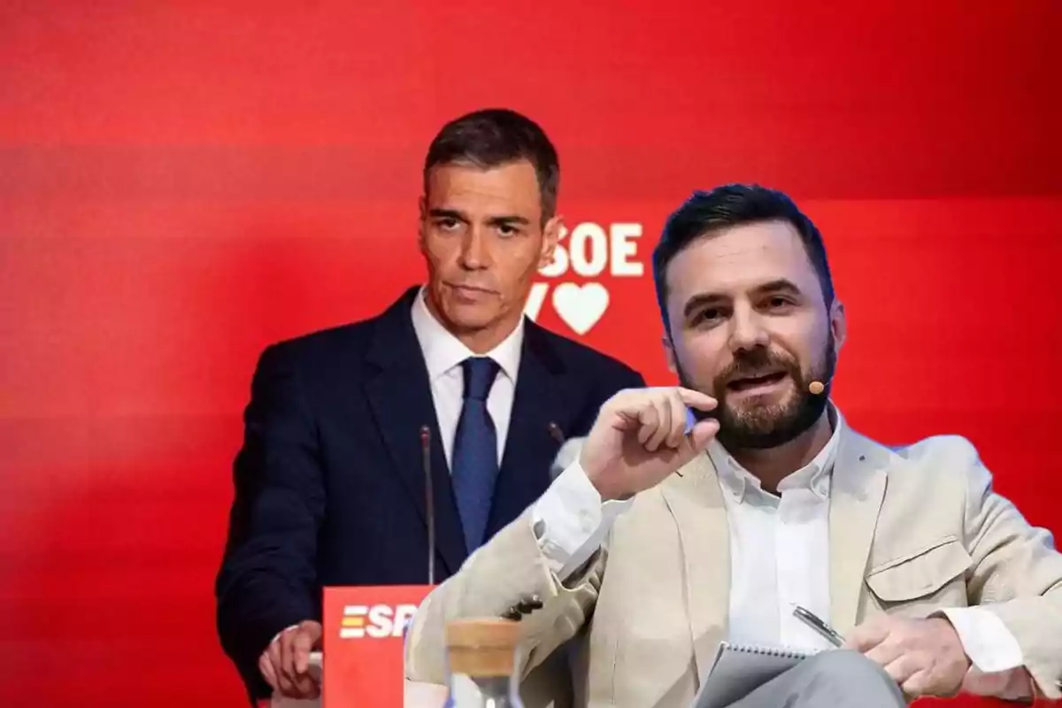 Dos hombres en un escenario con fondo rojo y logotipo del PSOE uno de ellos de pie con traje oscuro y el otro sentado con chaqueta clara y micrófono en la mejilla