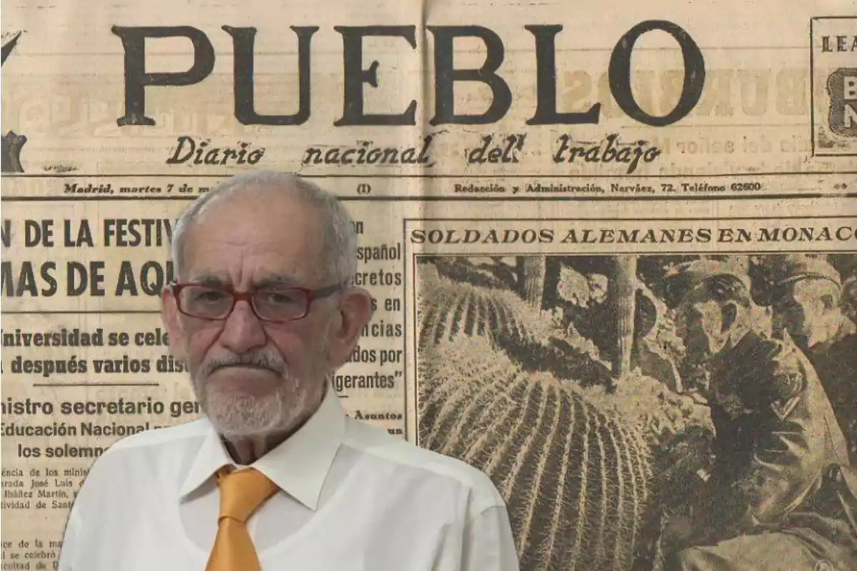 Un hombre mayor con gafas y corbata naranja está frente a una portada de periódico antiguo que dice "PUEBLO Diario nacional del trabajo".