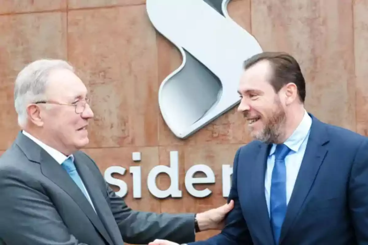 Dos hombres de traje se saludan frente a un edificio con un logotipo grande en la pared.