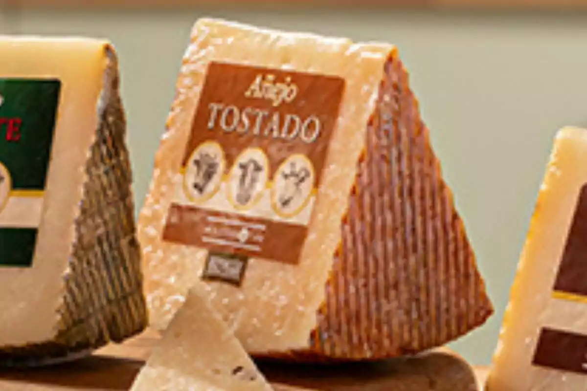 Un trozo de queso añejo tostado con una etiqueta marrón y detalles en dorado. Un trozo de queso añejo tostado con una etiqueta marrón y detalles en dorado.