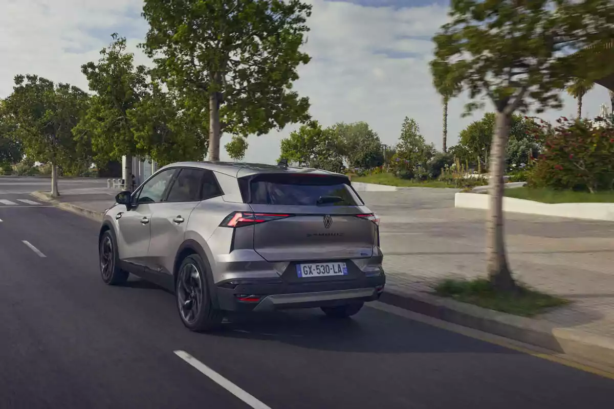 Un Renault Symbioz Hybrid plateado circula por una carretera rodeada de árboles y vegetación. Un Renault Symbioz Hybrid plateado circula por una carretera rodeada de árboles y vegetación.