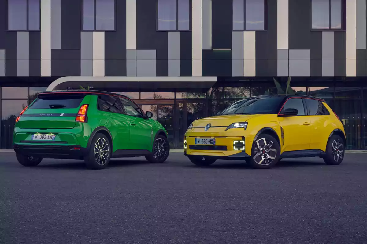 Dos autos Renault 5, uno verde y otro amarillo, estacionados frente a un edificio moderno.