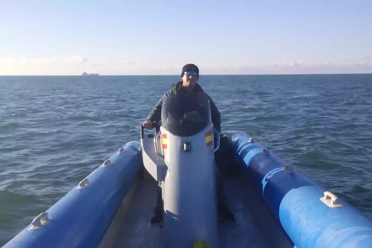 Persona conduciendo una lancha inflable en el mar con un cielo despejado y un barco en el horizonte.