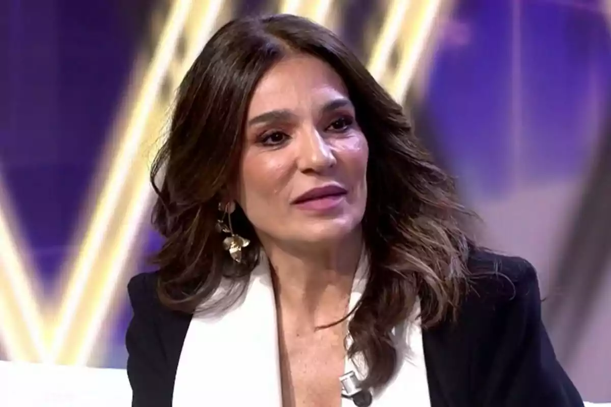 Raquel Bolo con cabello oscuro y suelto, usando un blazer negro y blusa blanca, en un entorno iluminado en De Viernes.