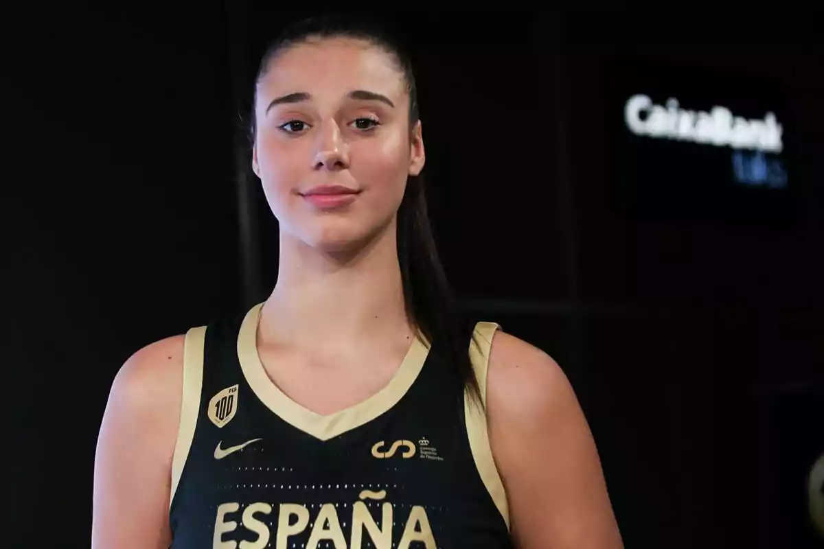 Una jugadora de baloncesto con uniforme de España posando frente a un fondo oscuro. Una jugadora de baloncesto con uniforme de España posando frente a un fondo oscuro.