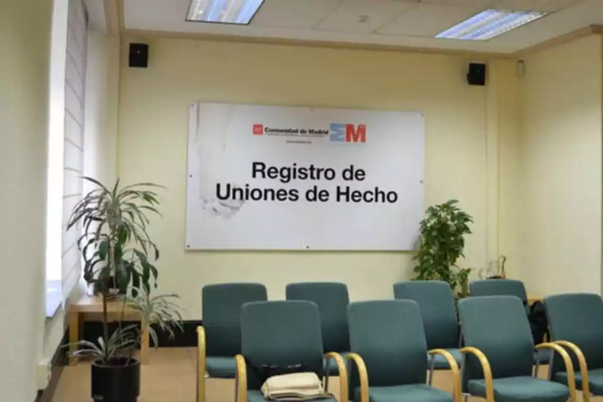 Sala de espera del Registro de Uniones de Hecho de la Comunidad de Madrid con sillas verdes y plantas decorativas.