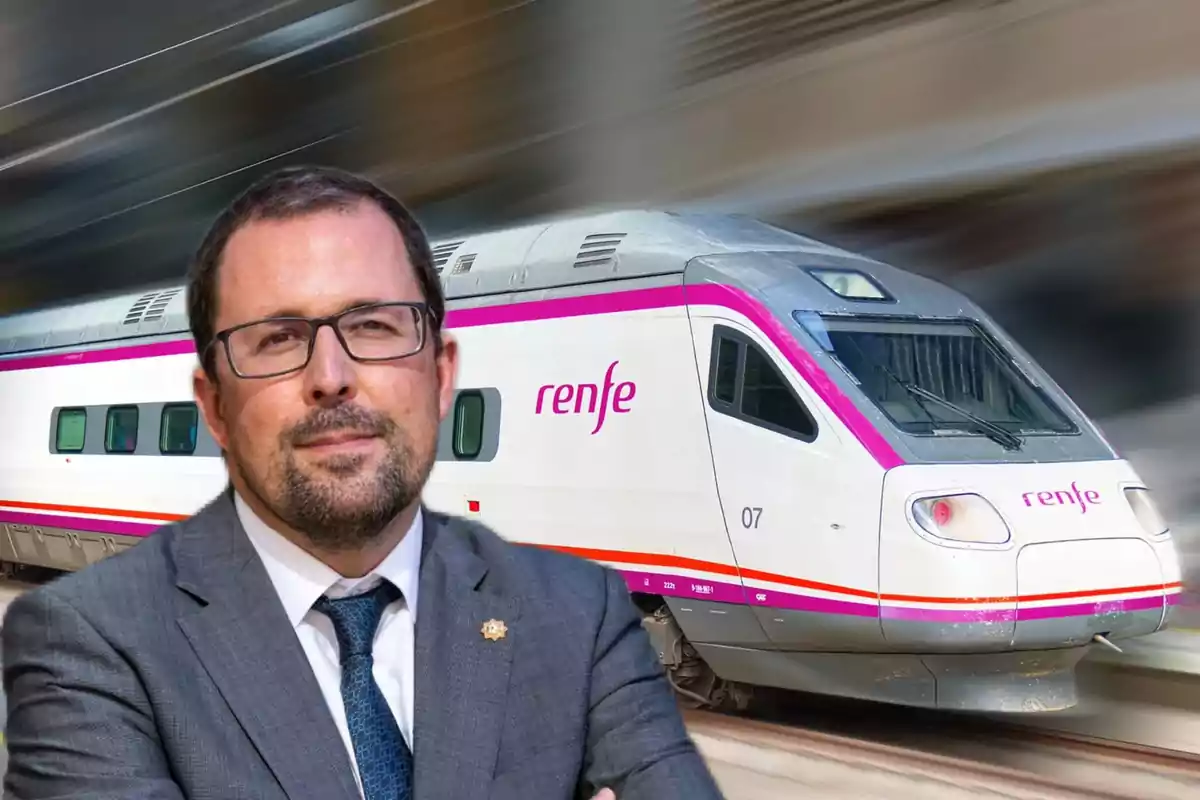 Un hombre con gafas y traje frente a un tren de Renfe en movimiento.