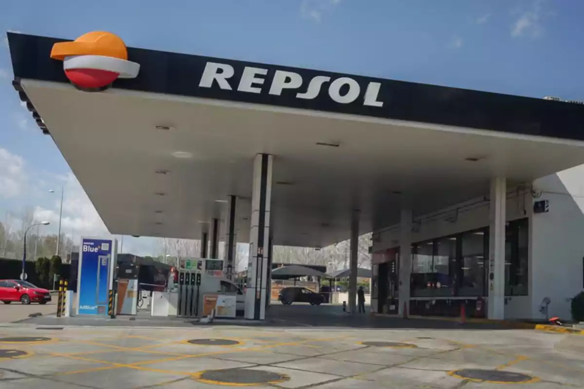 Estación de servicio Repsol con surtidores de combustible y autos estacionados en un día soleado Estación de servicio Repsol con surtidores de combustible y autos estacionados en un día soleado