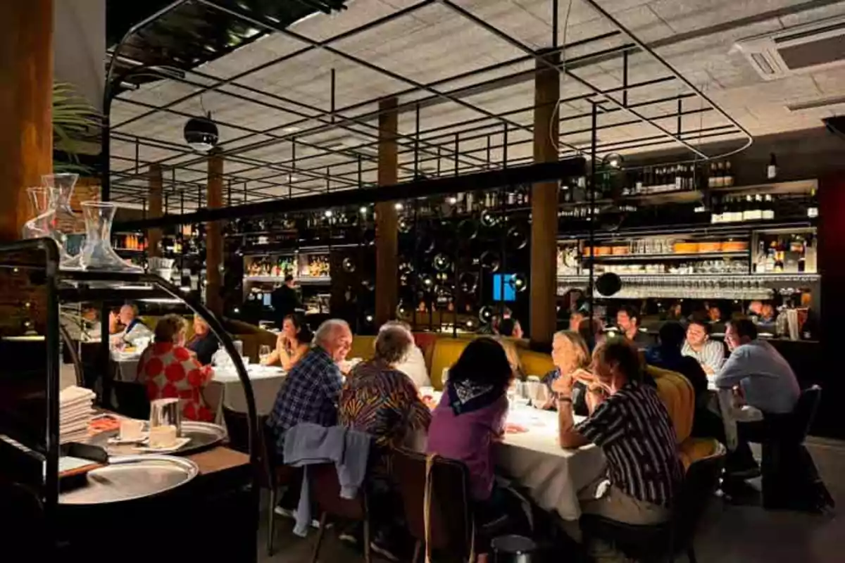 Personas cenando en un restaurante elegante con iluminación tenue y decoración moderna.