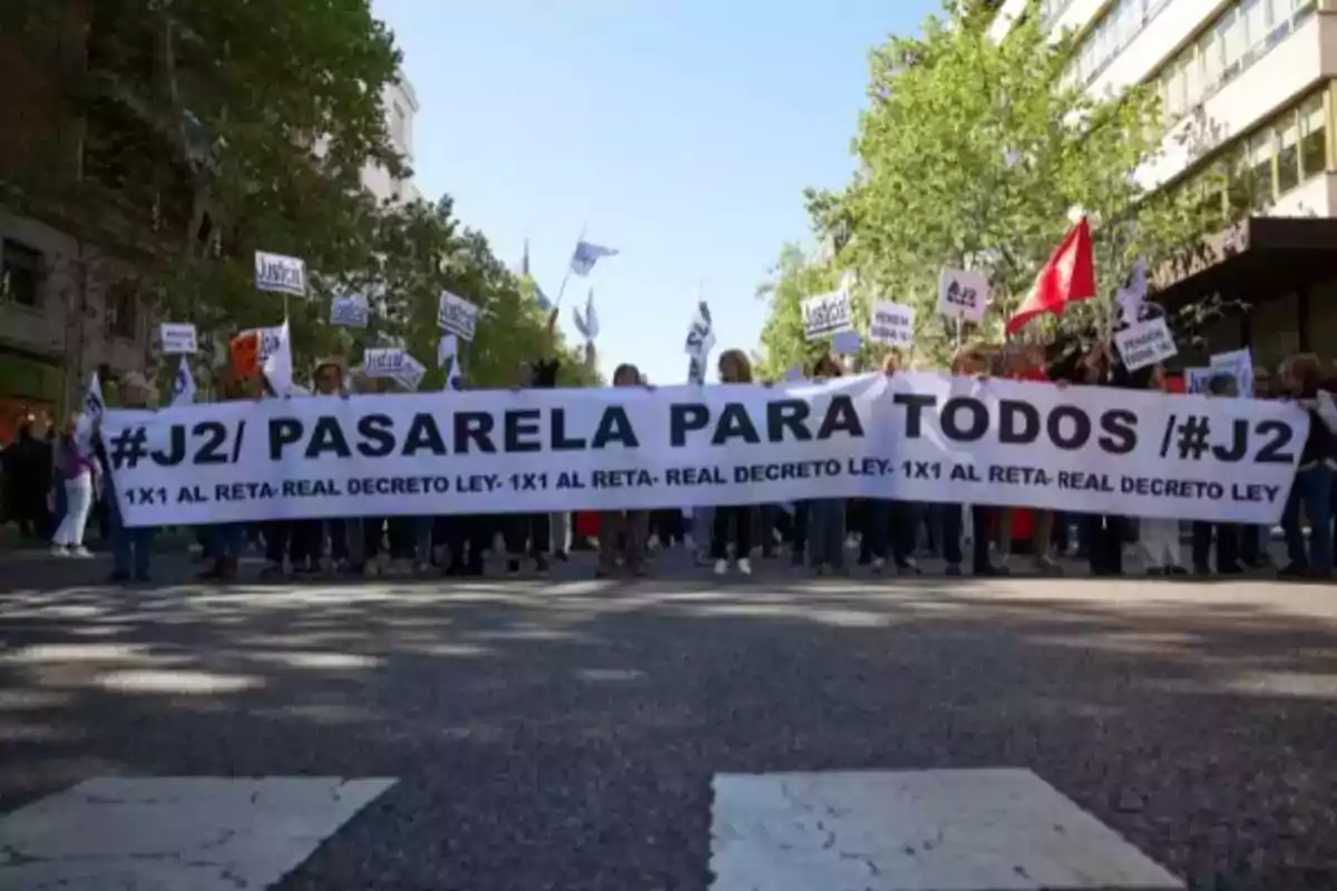 Un grupo de personas marcha por la calle sosteniendo una pancarta que dice 