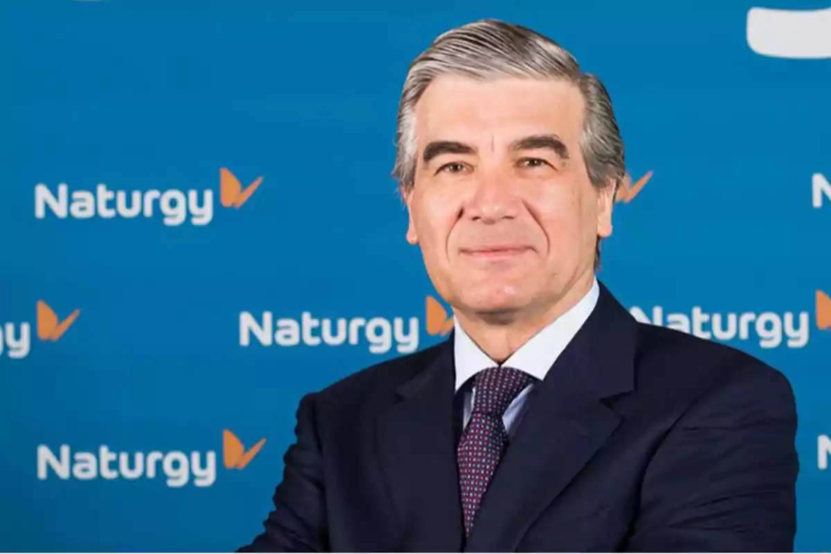 Hombre de traje frente a un fondo azul con el logo de Naturgy.