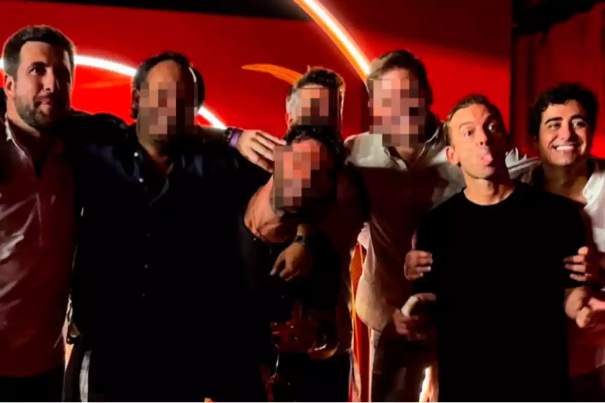 Un grupo de hombres posando juntos frente a un fondo rojo, algunos con los rostros pixelados y uno sacando la lengua.
