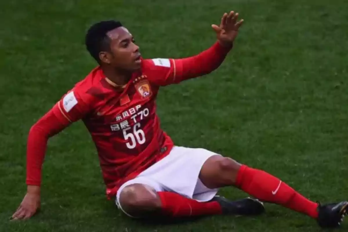 Jugador de fútbol con uniforme rojo sentado en el césped durante un partido.