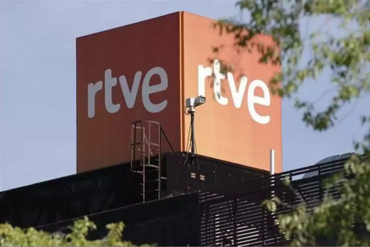 Edificio con un letrero grande de "rtve" en la parte superior, rodeado de árboles.