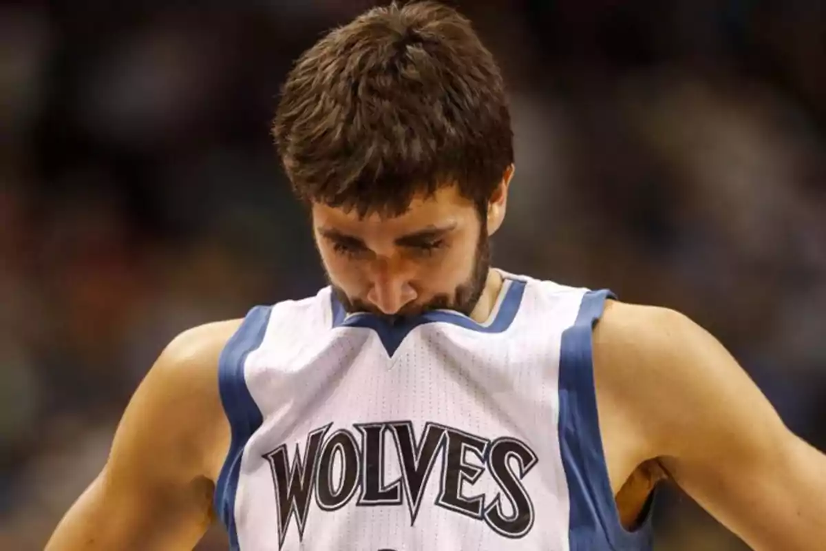 Jugador de baloncesto con uniforme de los Wolves mirando hacia abajo y mordiendo su camiseta durante un partido Jugador de baloncesto con uniforme de los Wolves mirando hacia abajo y mordiendo su camiseta durante un partido