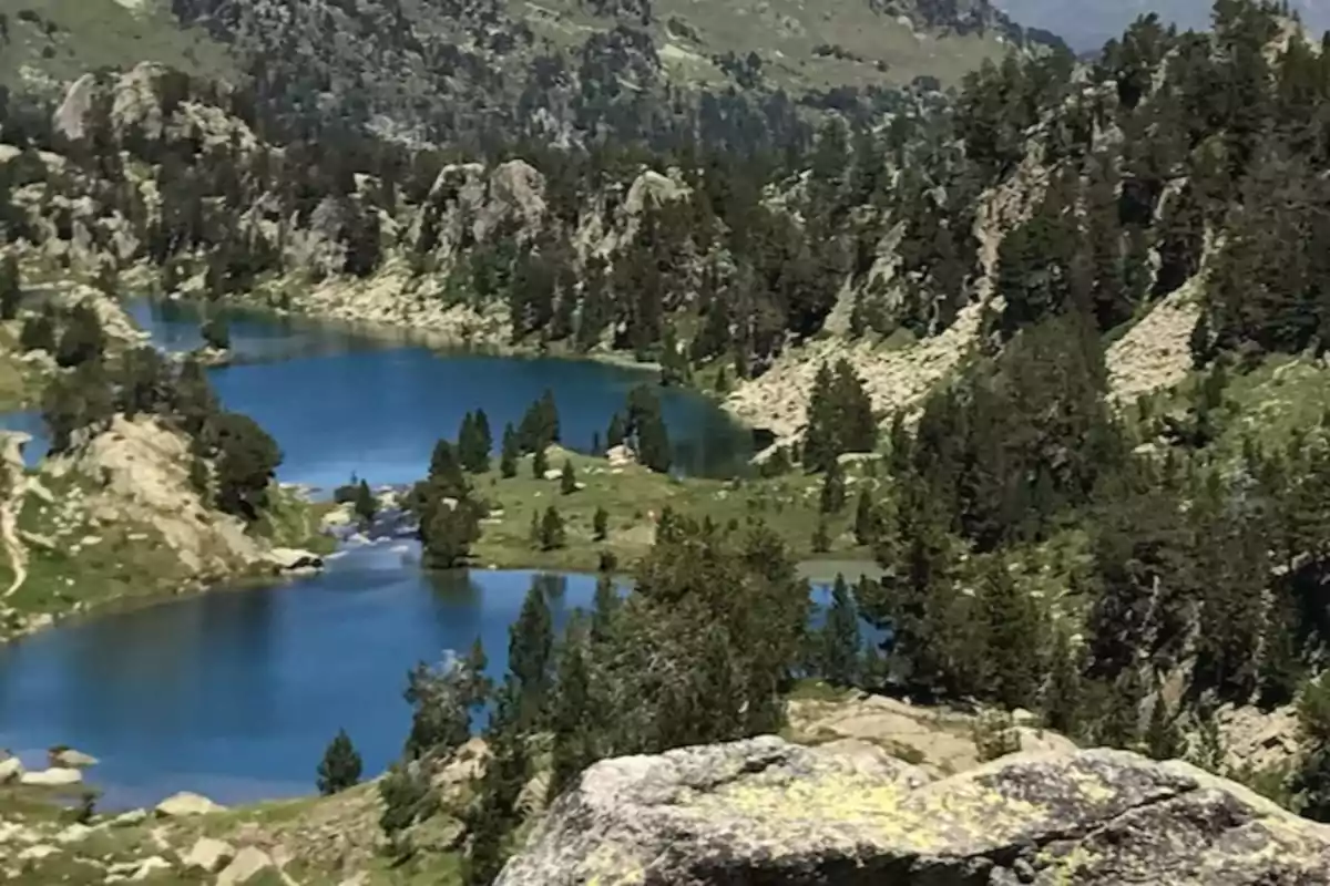 Un hermoso paisaje montañoso con un lago azul rodeado de árboles y formaciones rocosas.