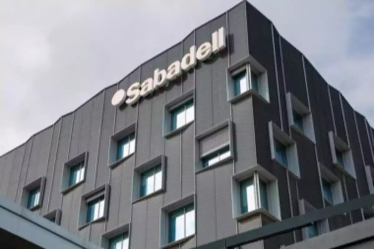 Edificio moderno de color gris con el logotipo de Sabadell en la parte superior Edificio moderno de color gris con el logotipo de Sabadell en la parte superior