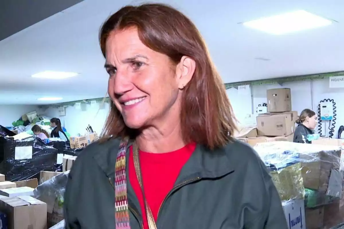 Samantha Vallejo-Nágera sonriendo en un almacén lleno de cajas y personas trabajando al fondo.