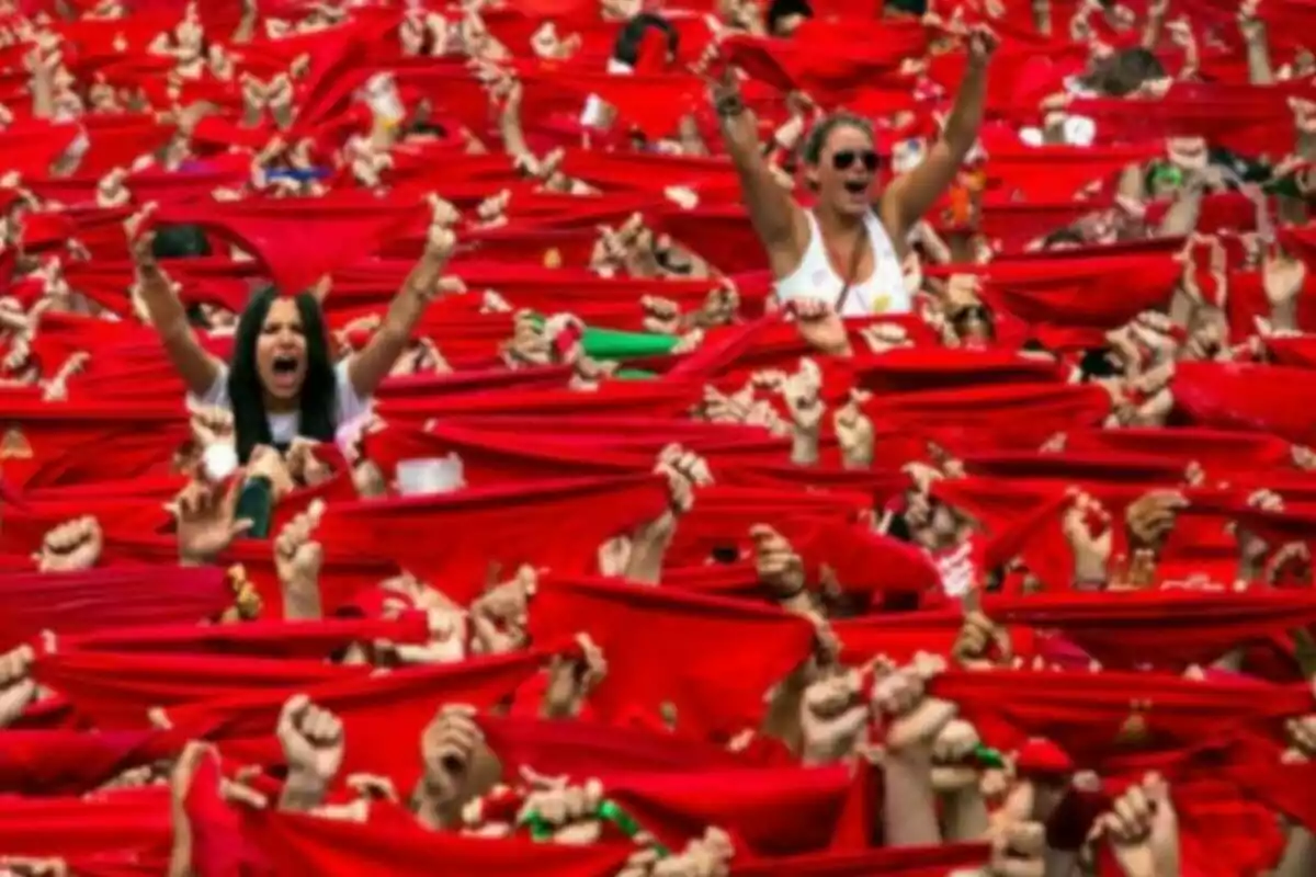 Multitud de personas levantando pañuelos rojos en un evento festivo. Multitud de personas levantando pañuelos rojos en un evento festivo.