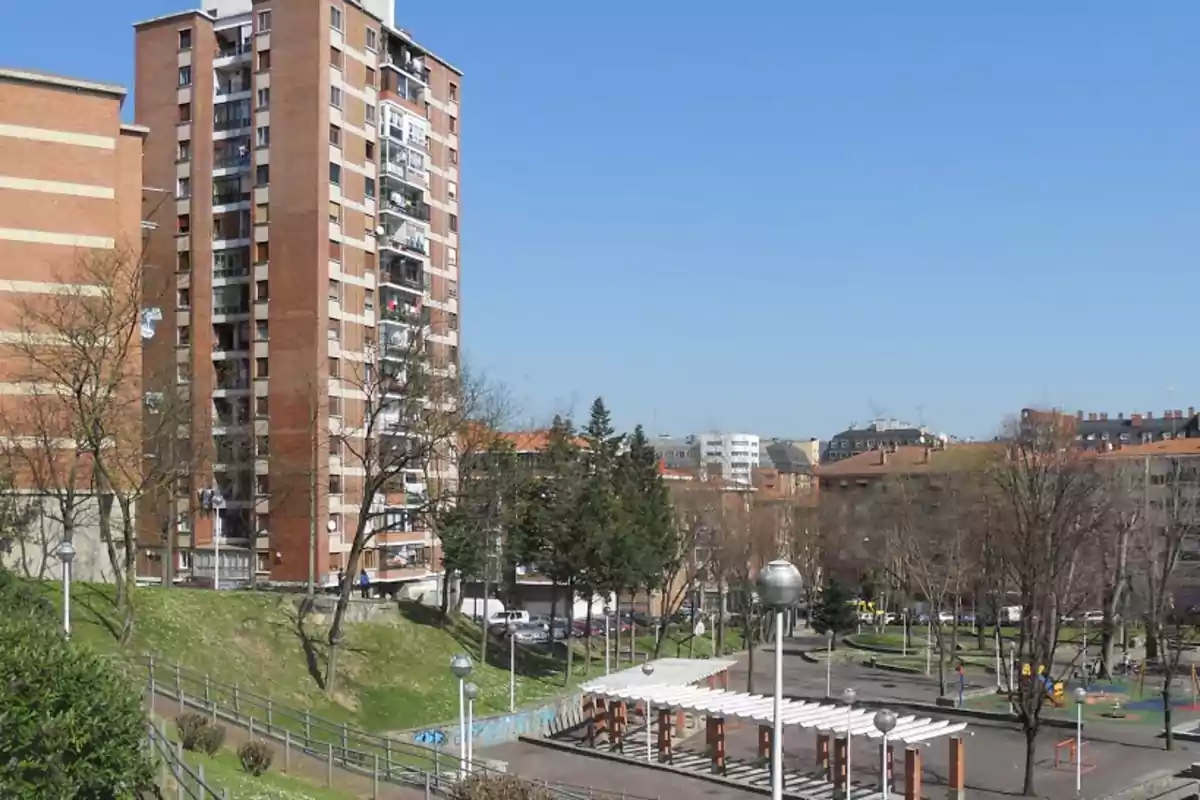 Edificios residenciales de ladrillo con un parque y una pérgola en primer plano bajo un cielo despejado.