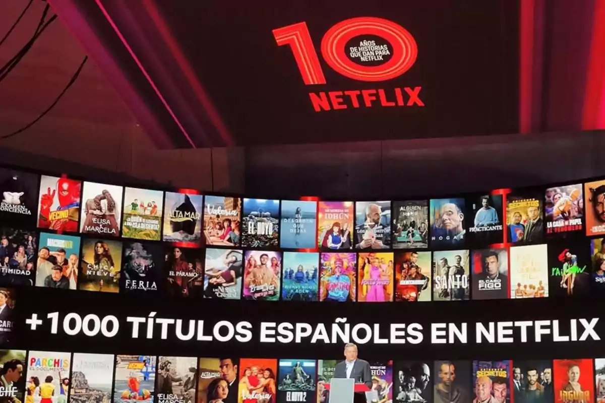 Escenario de evento de Netflix con una pantalla que muestra portadas de series y películas españolas y un mensaje que celebra más de mil títulos españoles en la plataforma Escenario de evento de Netflix con una pantalla que muestra portadas de series y películas españolas y un mensaje que celebra más de mil títulos españoles en la plataforma