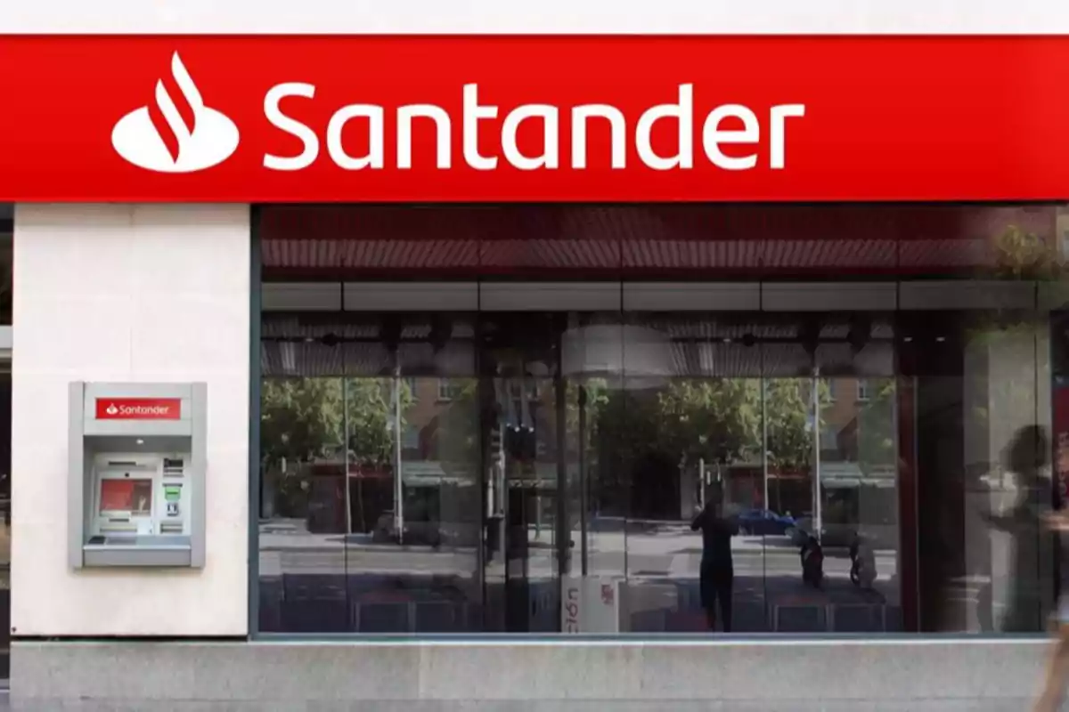 Fachada de una sucursal bancaria con un cajero automático en la pared y un letrero rojo con el nombre del banco. Fachada de una sucursal bancaria con un cajero automático en la pared y un letrero rojo con el nombre del banco.