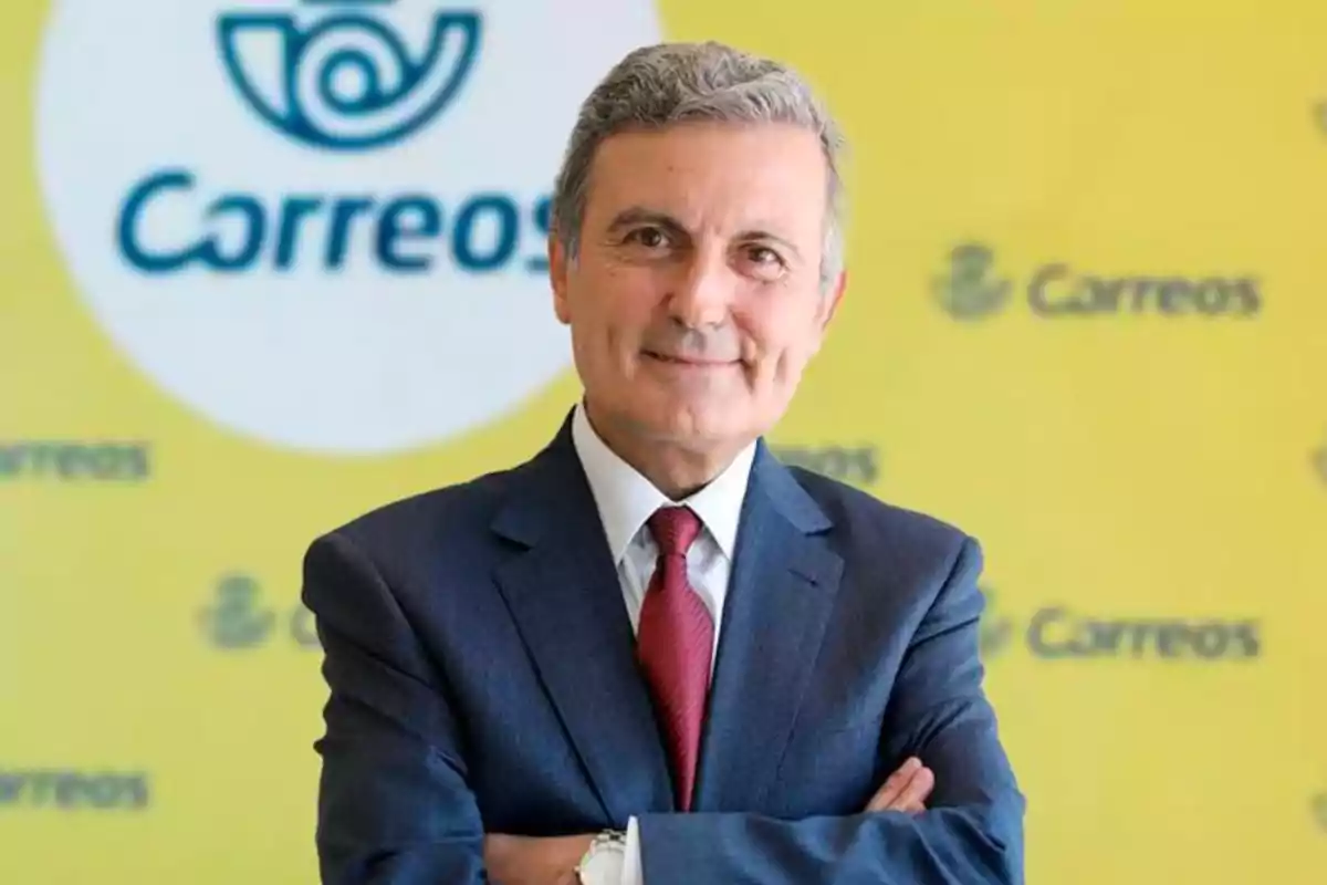 Un hombre de traje y corbata roja frente a un fondo amarillo con el logo de Correos.