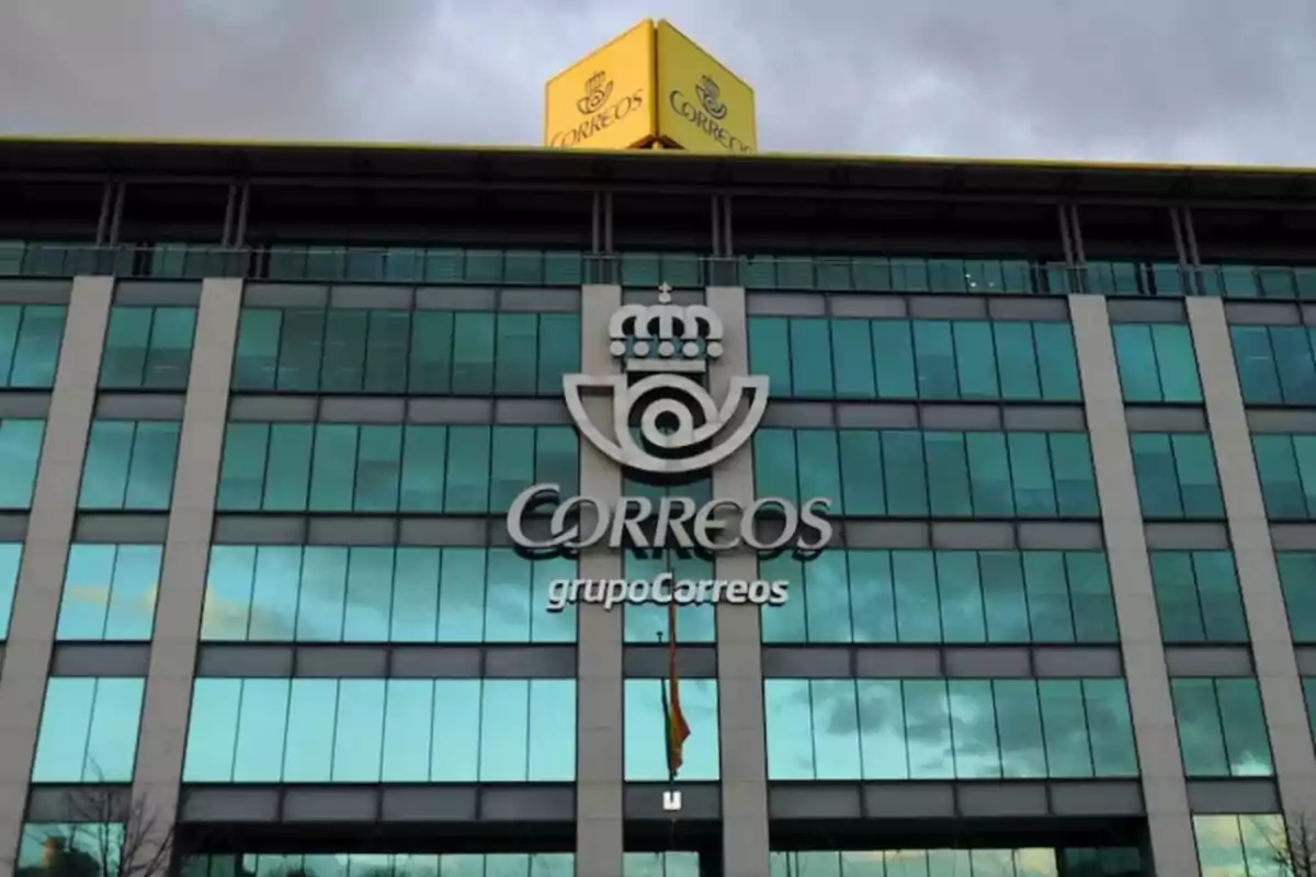 Edificio de Correos con fachada de vidrio y logotipo visible en el centro.