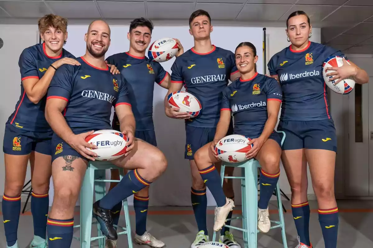 Un grupo de jugadores de rugby posando con uniformes azules y balones de rugby.