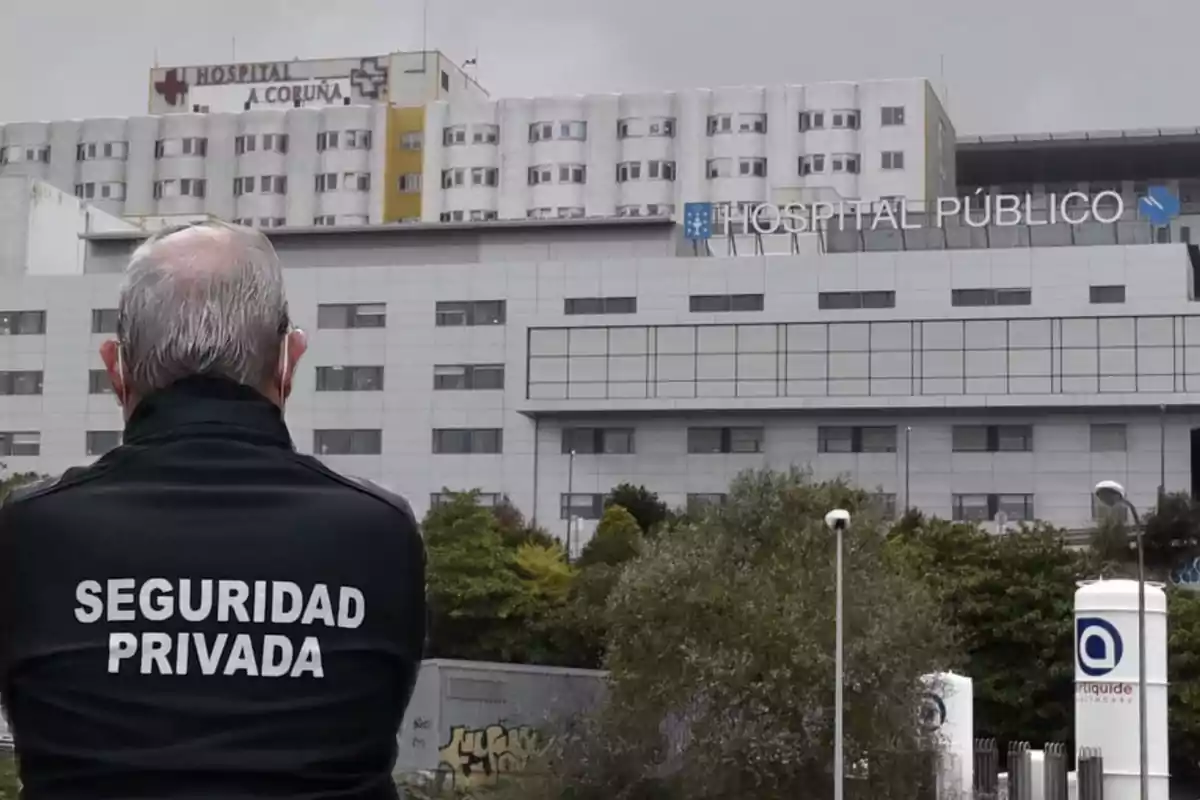 Un guardia de seguridad privada de espaldas frente a un hospital público.