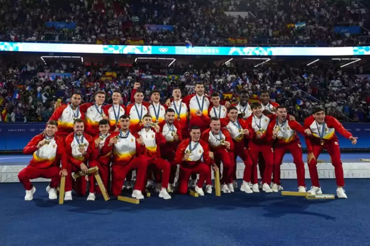 Equipo deportivo celebrando con medallas en un estadio lleno de espectadores.