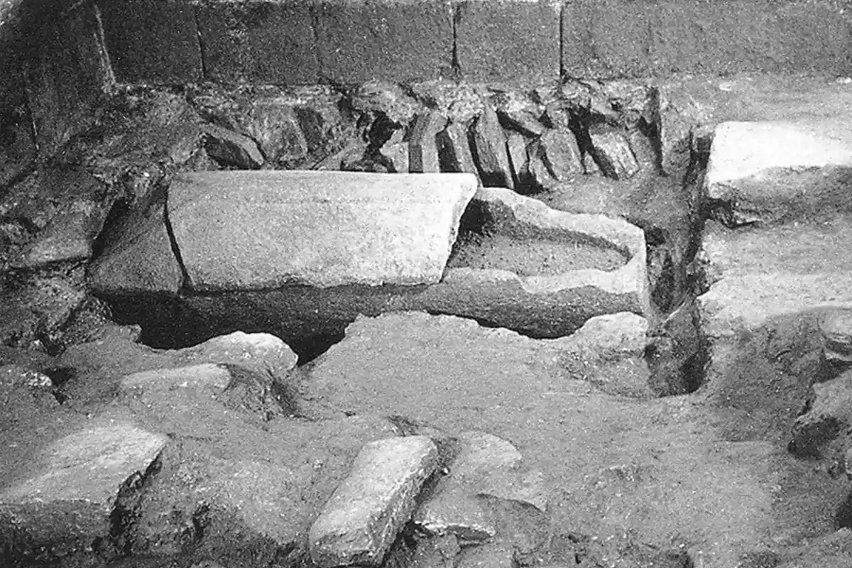 Excavación arqueológica mostrando una tumba de piedra antigua parcialmente descubierta.