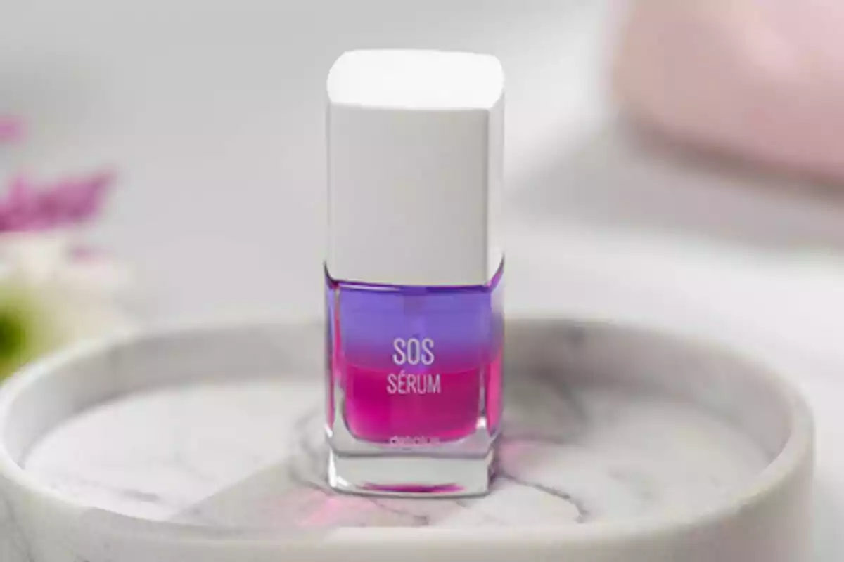 Frasco de sérum SOS con tapa blanca y líquido de colores rosa y morado sobre una bandeja de mármol Frasco de sérum SOS con tapa blanca y líquido de colores rosa y morado sobre una bandeja de mármol