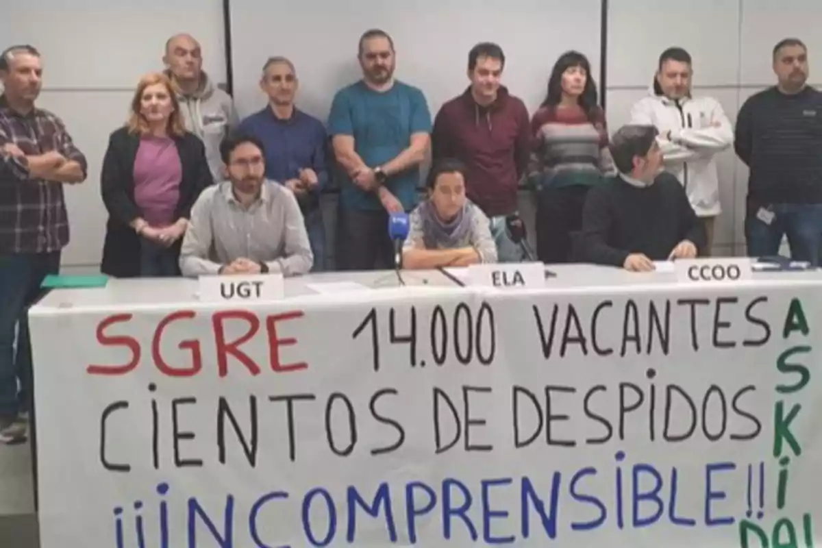 Un grupo de personas está reunido detrás de una mesa con un cartel que dice 