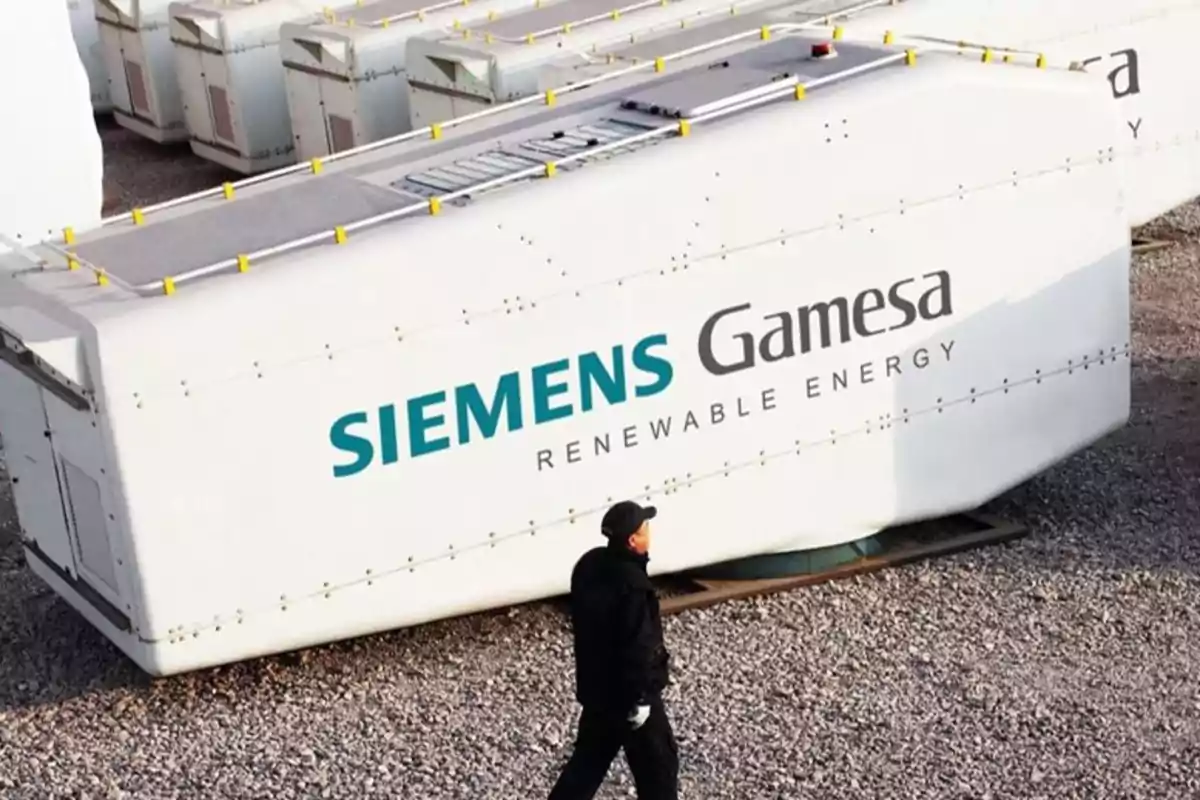 Hombre caminando frente a una estructura de Siemens Gamesa Renewable Energy en un área de almacenamiento al aire libre.