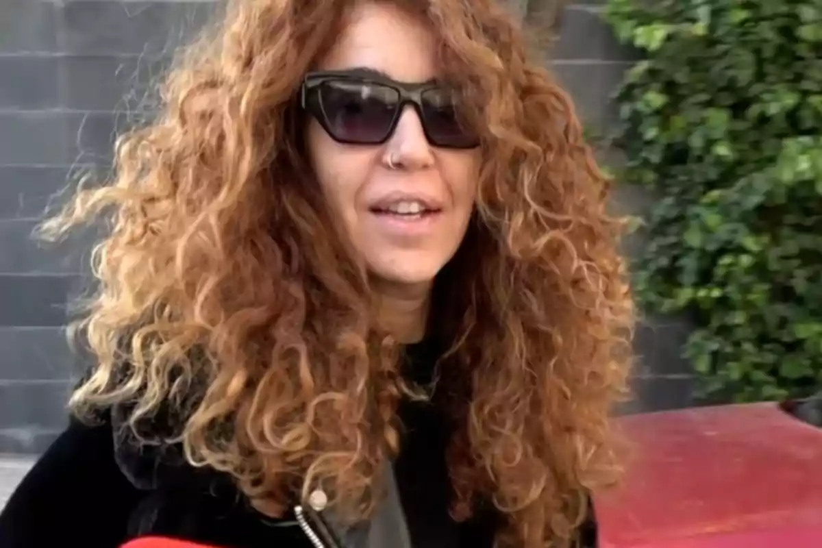 Sofía Cristo con cabello rizado y gafas de sol sonríe al aire libre.