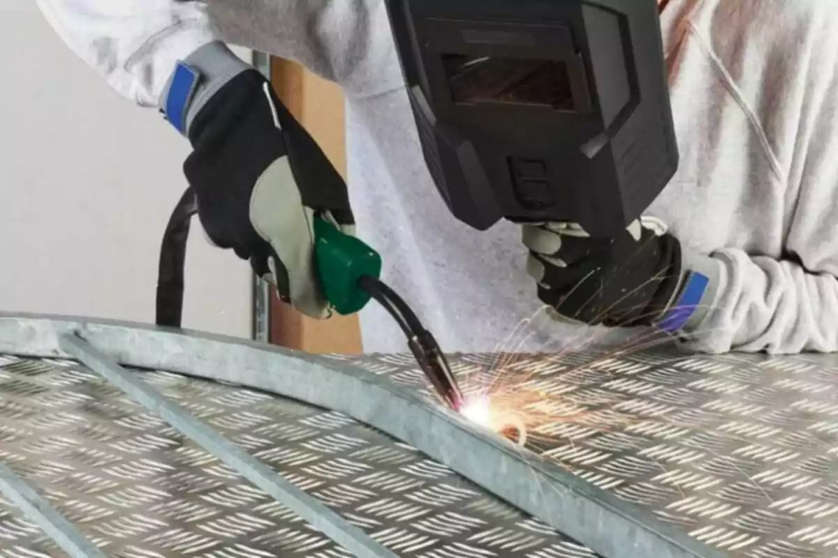 Persona soldando una estructura metálica con equipo de protección. Persona soldando una estructura metálica con equipo de protección.