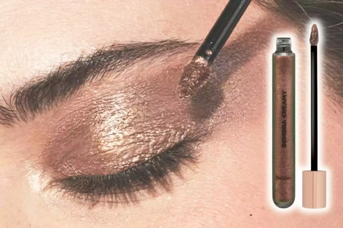 Aplicación de sombra de ojos cremosa en tono bronce sobre párpado cerrado con aplicador y el envase del producto de Mercadona al lado. Aplicación de sombra de ojos cremosa en tono bronce sobre párpado cerrado con aplicador y el envase del producto de Mercadona al lado.