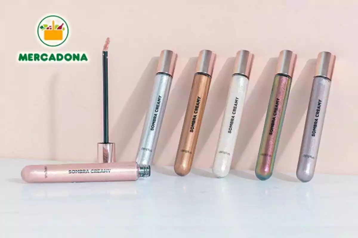 Una colección de sombras de ojos en formato líquido con aplicador de Mercadona, presentadas en envases cilíndricos de diferentes colores metálicos, junto al logo de una tienda. Una colección de sombras de ojos en formato líquido con aplicador de Mercadona, presentadas en envases cilíndricos de diferentes colores metálicos, junto al logo de una tienda.