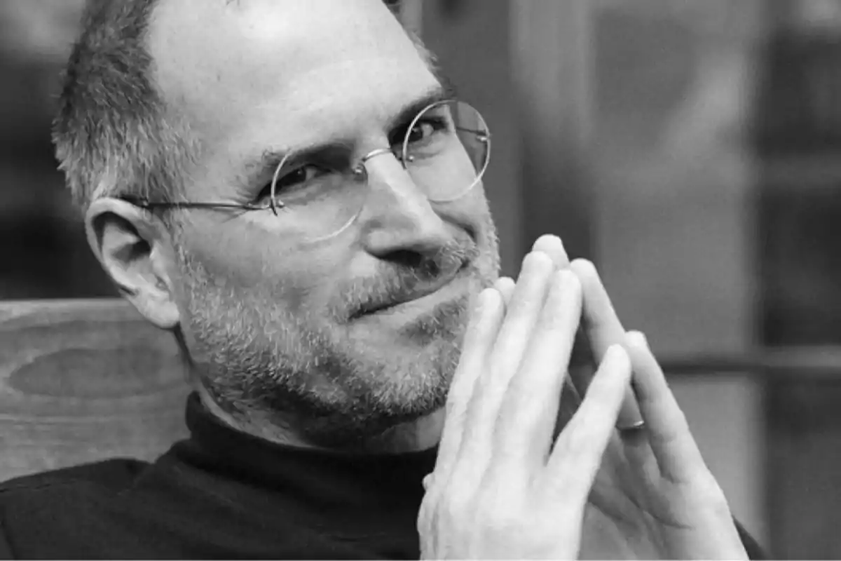 Hombre con gafas y barba, con las manos juntas frente a su rostro, en una imagen en blanco y negro.