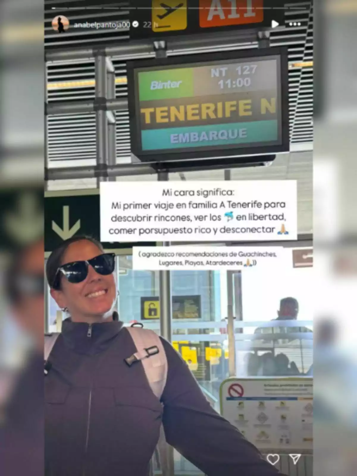 Anabel Pantoja sonriente con gafas de sol y mochila en un aeropuerto, frente a una pantalla que indica un vuelo a Tenerife. Anabel Pantoja sonriente con gafas de sol y mochila en un aeropuerto, frente a una pantalla que indica un vuelo a Tenerife.