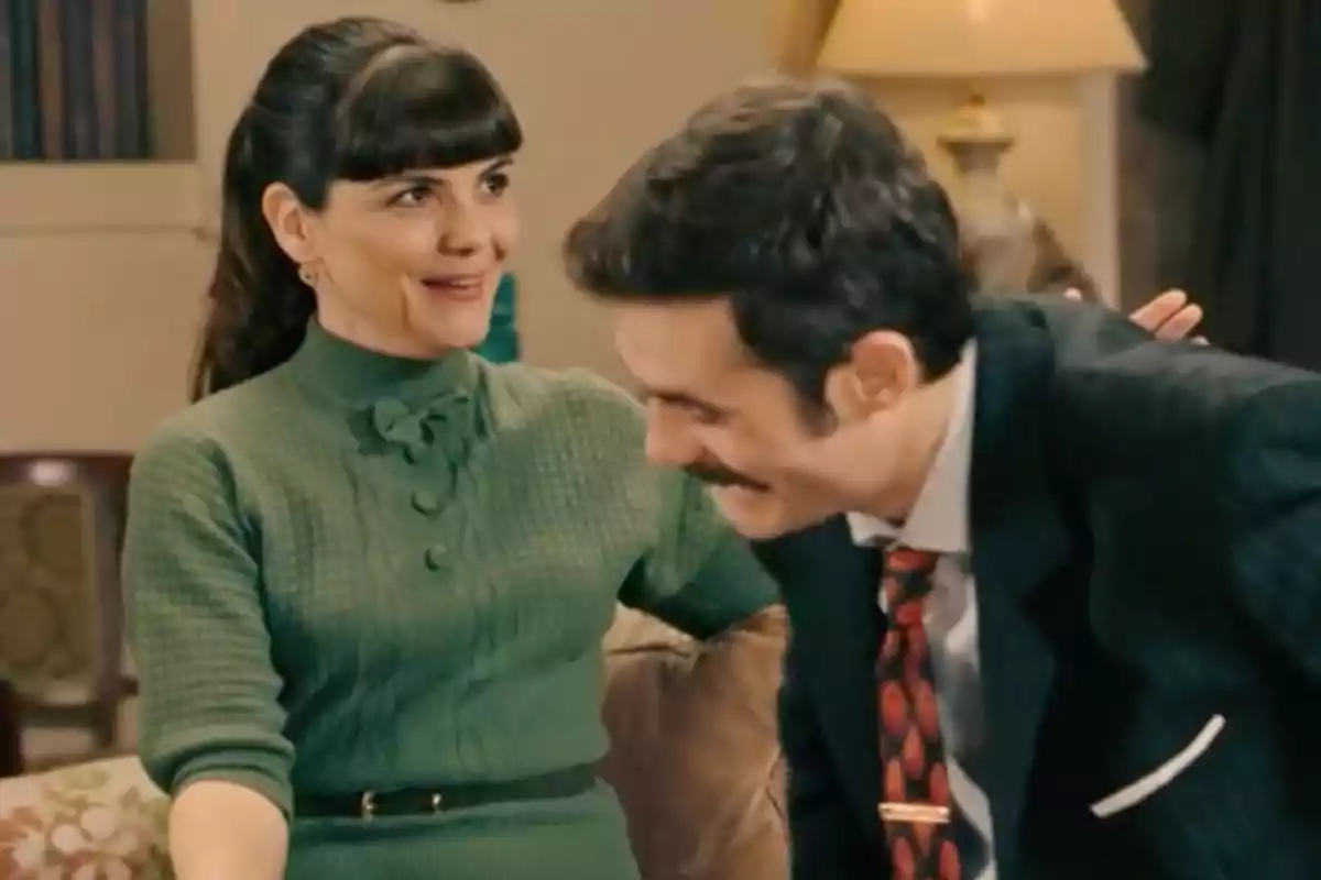 Gema con vestido verde sonríe mientras Joaquín con bigote y traje oscuro se inclina hacia ella en una sala iluminada. Captura de 'Sueños de libertad' Gema con vestido verde sonríe mientras Joaquín con bigote y traje oscuro se inclina hacia ella en una sala iluminada. Captura de 'Sueños de libertad'