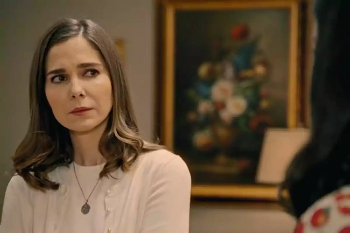 Natalia Sánchez con expresión pensativa está en una habitación con un cuadro de flores al fondo en Sueños de Libertad. Natalia Sánchez con expresión pensativa está en una habitación con un cuadro de flores al fondo en Sueños de Libertad.