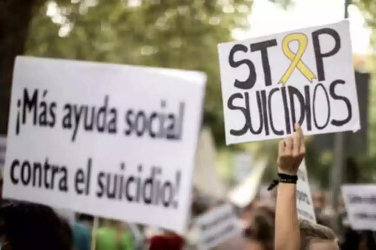 Personas sostienen pancartas en una manifestación que aboga por más ayuda social y la prevención del suicidio.