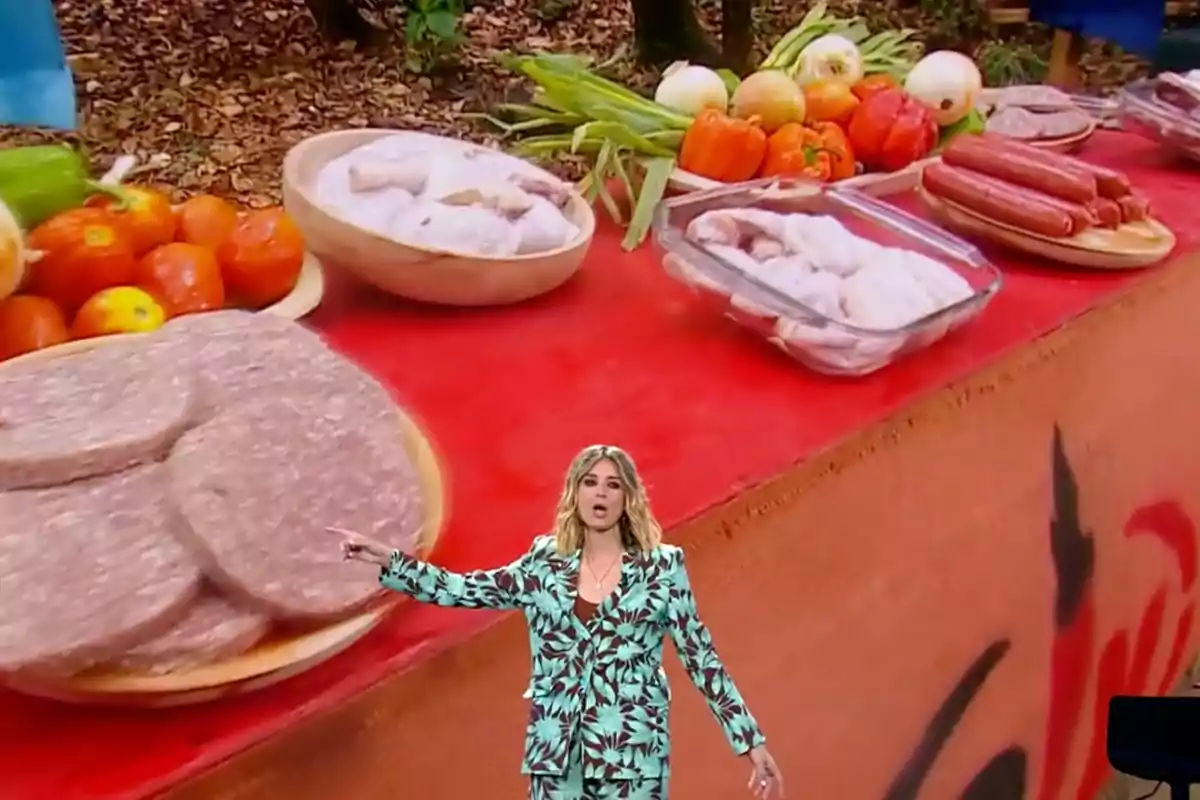 Sandra Barneda con un traje estampado está de pie frente a una mesa llena de alimentos como verduras, embutidos y carne cruda. Captura de 'Supervivientes' Sandra Barneda con un traje estampado está de pie frente a una mesa llena de alimentos como verduras, embutidos y carne cruda. Captura de 'Supervivientes'