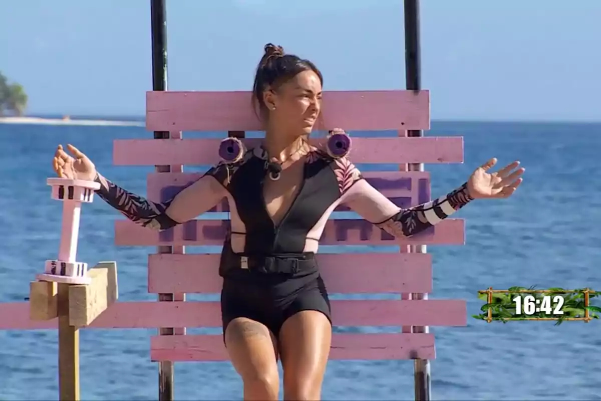 Anita con traje deportivo está sentada en una estructura de madera rosa frente al mar, con los brazos extendidos y un cronómetro en la esquina inferior derecha. Captura de 'Supervivientes' Anita con traje deportivo está sentada en una estructura de madera rosa frente al mar, con los brazos extendidos y un cronómetro en la esquina inferior derecha. Captura de 'Supervivientes'