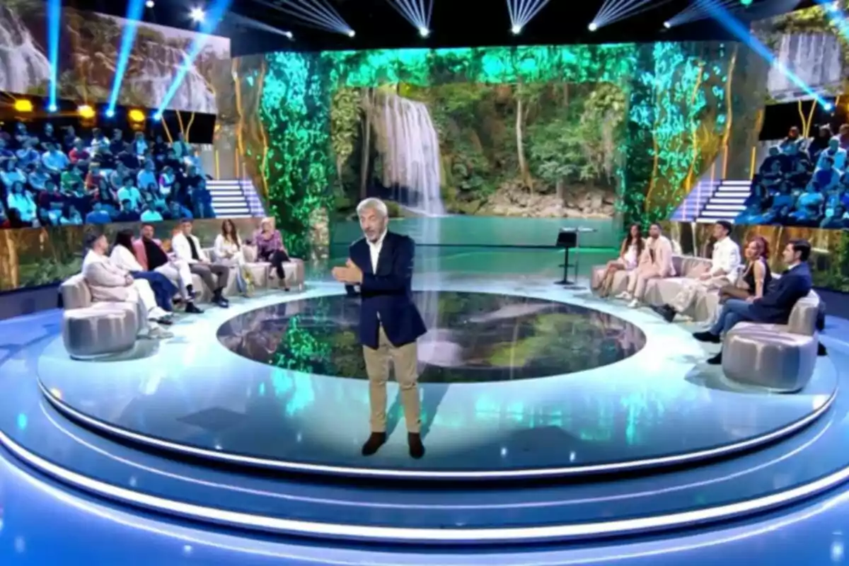 Carlos Sobera está en un estudio de televisión con un fondo de cascada y público sentado alrededor. Captura de 'Supervivientes' Carlos Sobera está en un estudio de televisión con un fondo de cascada y público sentado alrededor. Captura de 'Supervivientes'