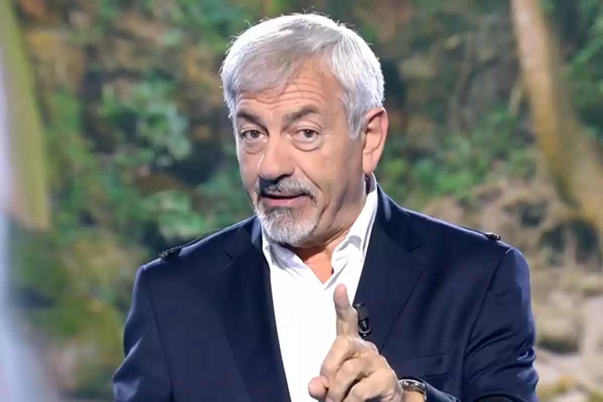 Carlos Sobera está hablando y gesticulando con el dedo índice levantado, vistiendo un traje oscuro y camisa blanca, con un fondo de naturaleza desenfocado. Captura de 'Supervivientes' Carlos Sobera está hablando y gesticulando con el dedo índice levantado, vistiendo un traje oscuro y camisa blanca, con un fondo de naturaleza desenfocado. Captura de 'Supervivientes'