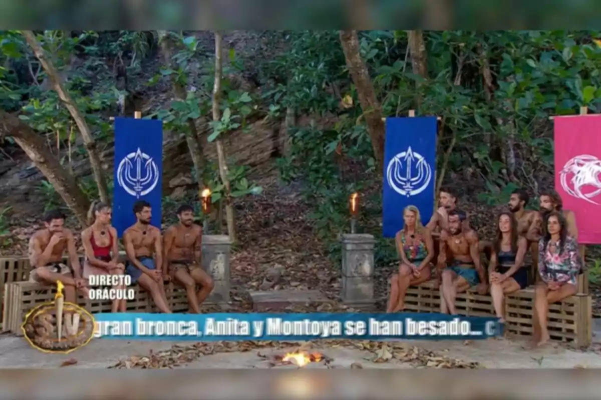 Un grupo de personas sentadas en un entorno selvático, con antorchas encendidas y banderas de colores detrás de ellos, mientras un texto en la parte inferior menciona un evento reciente. Captura de 'Supervivientes' Un grupo de personas sentadas en un entorno selvático, con antorchas encendidas y banderas de colores detrás de ellos, mientras un texto en la parte inferior menciona un evento reciente. Captura de 'Supervivientes'