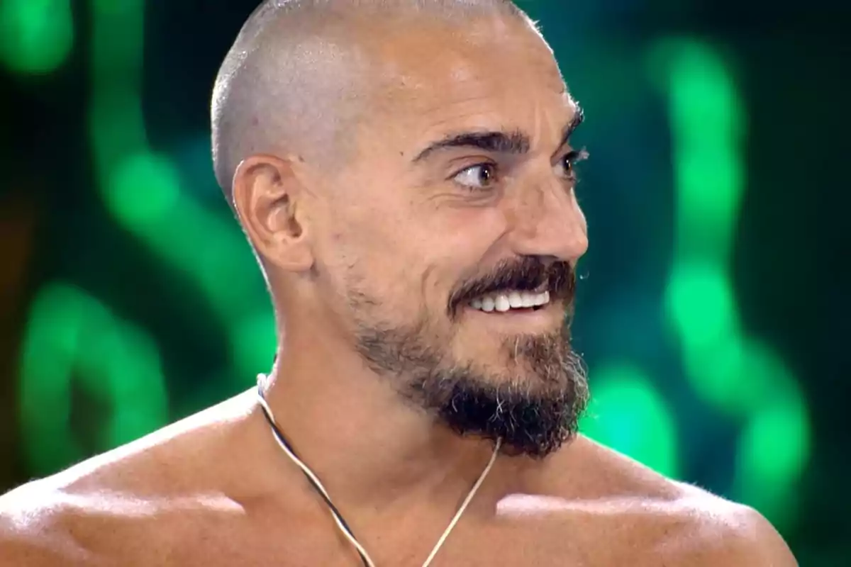 Damián Quintero sonríe mirando hacia la derecha con fondo desenfocado de luces verdes. Captura de 'Supervivientes' Damián Quintero sonríe mirando hacia la derecha con fondo desenfocado de luces verdes. Captura de 'Supervivientes'